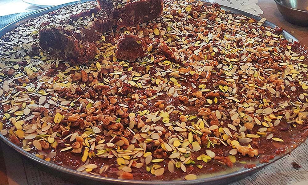 A tray of fresh desi ghee sohn halwa topped with almonds, pistachios and walnuts